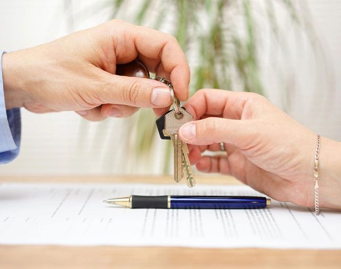 Two people holding keys to a house